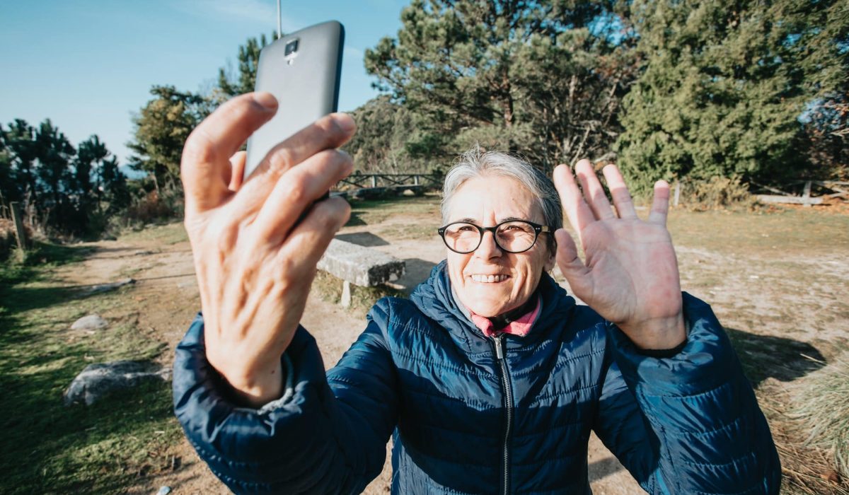 Happy old woman with gray hair enjoying outdoor excursion in mountain landscape