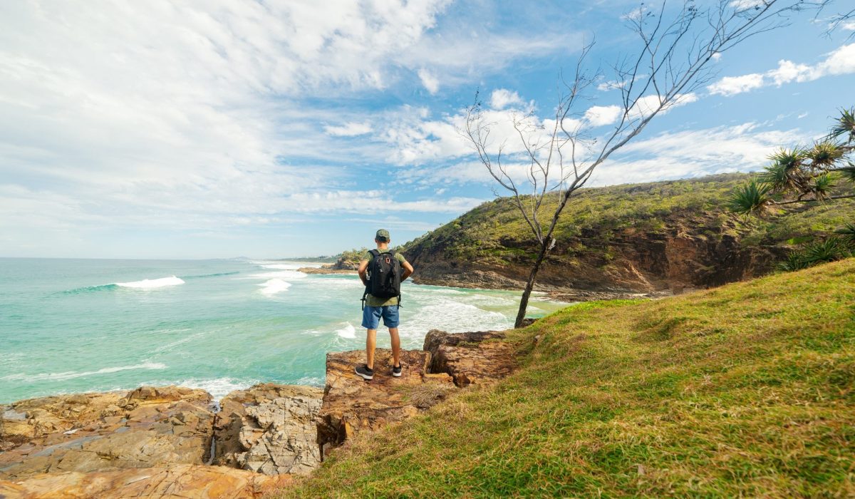 Man Standing on Cliff Looking at Seashore in Summer in Noosa, Queensland, Australia.Explorer Concept