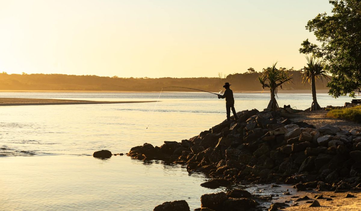 Silhouette of Man Standing on Rock Fishing at Sunset Time in Noosa, Queensland, Australia